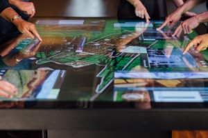 A 3D model of Cusco and media windows are visible on a large multitouch table